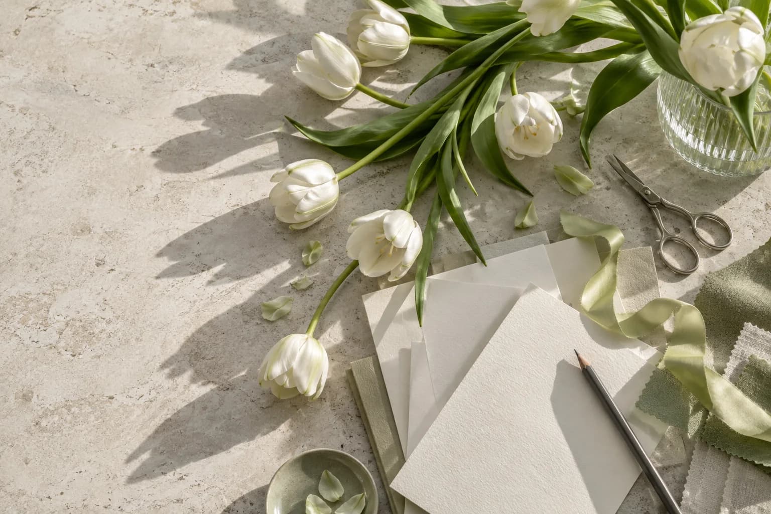 A working table seen from above with tulips, paper samples, scissors and ribbon
