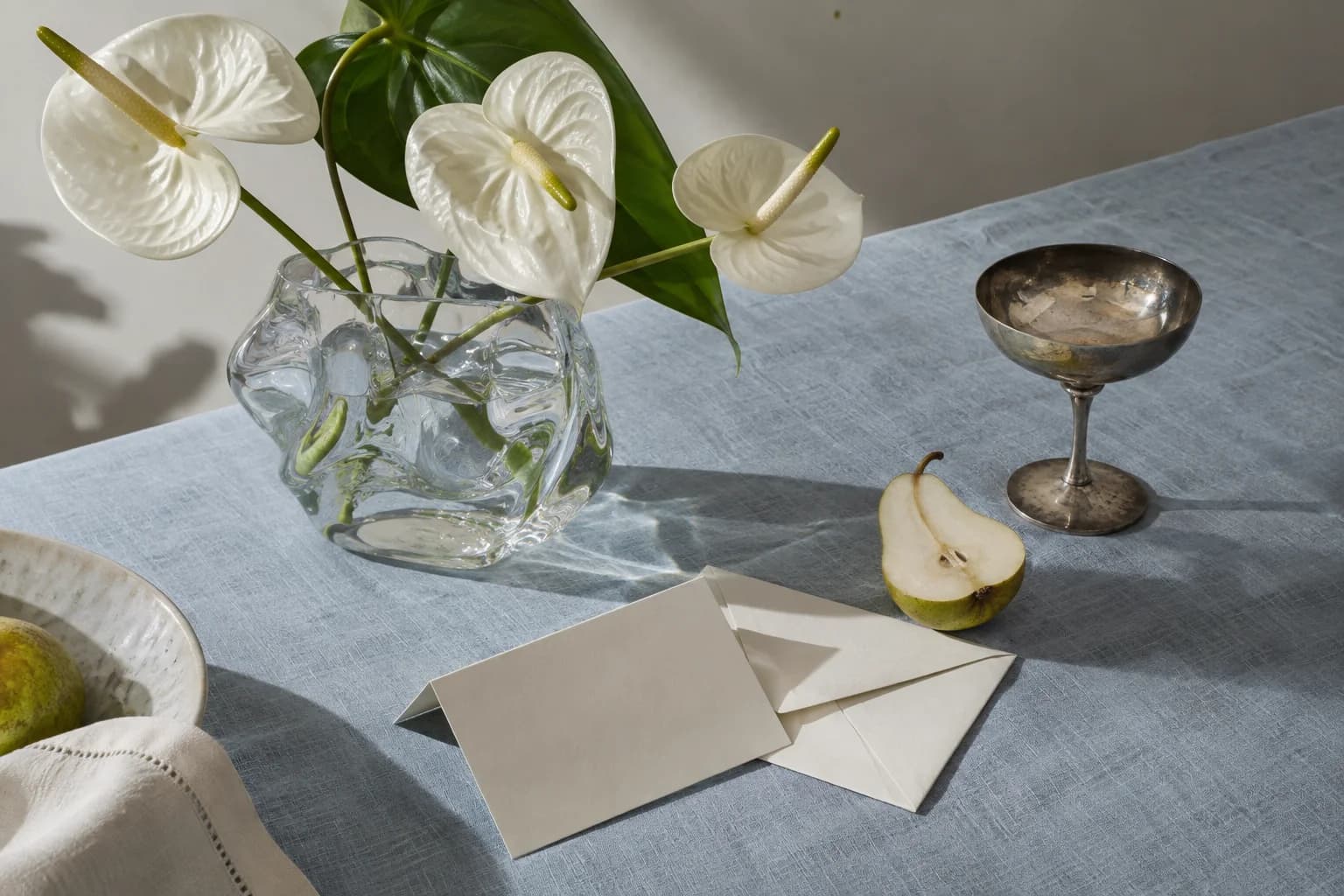 Anthuriums, a silver coupe and blank stationery on blue linen